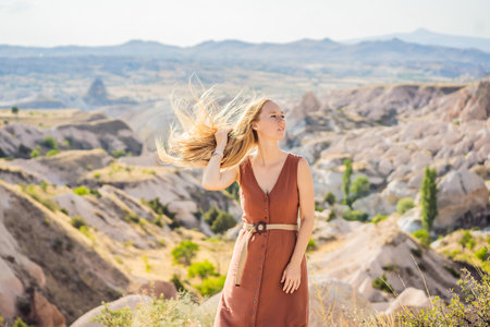 Young woman exploring valley with rock formations and fairy caves near Goreme in Cappadocia Turkeyの写真素材