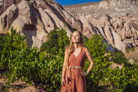 Young woman exploring valley with rock formations and fairy caves near Goreme in Cappadocia Turkey