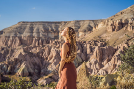 Young woman exploring valley with rock formations and fairy caves near Goreme in Cappadocia Turkey