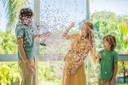 Its a girl. Expectant parents mother, father and their elder son are having a gender reveal party. A married the couple burst the balloon and the pink confetti flew out. Family, pregnancy and prenatal care conceptの写真素材