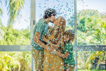 Its a boy. Expectant parents mother, father and their elder son are having a gender reveal party. A married the couple burst the balloon and the blue confetti flew out. Family, pregnancy and prenatal care conceptの写真素材