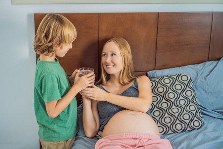 Son brought his pregnant mother a glass of waterの写真素材