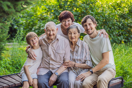Four generations of family spend time together in the park. Elderly couple. Senior husband and wife holding hands and bonding with true emotionsの写真素材