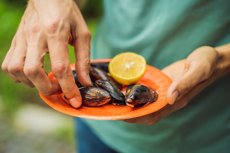 Heap of mussels in shells stuffed with rice. Man is going to eat midye traditional Turkish food. Istanbul, Turkeyの写真素材