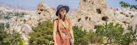 Young woman exploring valley with rock formations and fairy caves near Goreme in Cappadocia Turkey...