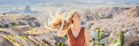 BANNER, LONG FORMAT Young woman exploring valley with rock formations and fairy caves near Goreme in Cappadocia Turkeyの写真素材