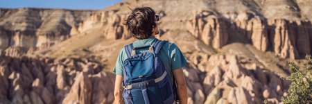 BANNER, LONG FORMAT Young man exploring valley with rock formations and fairy caves near Goreme in Cappadocia Turkeyの写真素材