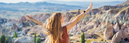 BANNER, LONG FORMAT Young woman exploring valley with rock formations and fairy caves near Goreme in Cappadocia Turkeyの写真素材