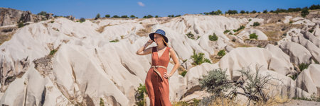 BANNER, LONG FORMAT Young woman exploring valley with rock formations and fairy caves near Goreme in...