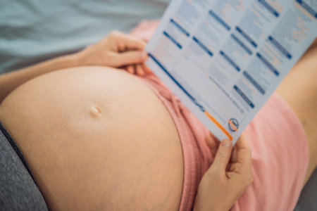 A pregnant woman looks at the results of a blood test printed on paperの写真素材