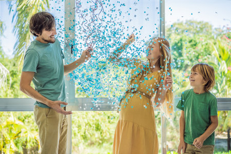 Its a boy. Expectant parents mother, father and their elder son are having a gender reveal party. A married the couple burst the balloon and the blue confetti flew out. Family, pregnancy and prenatal care conceptの写真素材