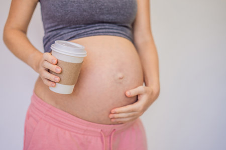 A pregnant woman holds a cup of coffee in her hands. Caffeine safety, myths about coffee during pregnancy conceptの写真素材