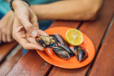 Heap of mussels in shells stuffed with rice. Man is going to eat midye traditional Turkish food. Istanbul, Turkeyの写真素材