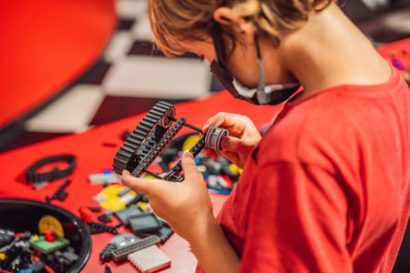 A boy in a medical mask plays with a constructor. child playing and building with colorful plastic...
