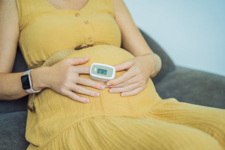 Pregnant woman with pulse oximeter on finger. Doctor measuring oxygen saturation level while visiting expectant mother with coronavirus disease at home, cropped. Pregnancy and covid-19 conceptの写真素材