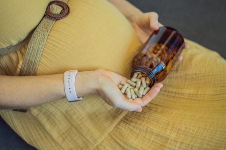 Prenatal Vitamins. Portrait Of Beautiful Smiling Pregnant Woman Holding Transparent Glass Jar With Pills, Taking Supplements For Healthy Pregnancy While Sitting On Couch At Home, Free Spaceの写真素材
