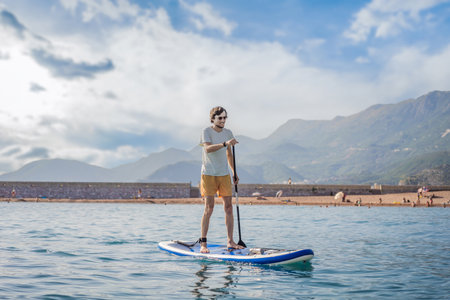 Young men Having Fun Stand Up Paddling in blue water sea near st stefan island in Montenegro. SUPの写真素材