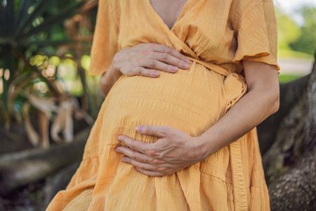 A serene and radiant pregnant woman after 40, surrounded by natures beauty in the park, cherishing the journey of motherhood with a glowing smileの写真素材
