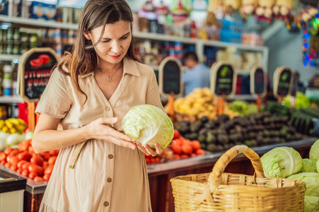 A glowing pregnant woman after forty makes a healthy choice as she selects organic vegetables and fruits at the vibrant organic market, prioritizing her well-being and her babys healthの写真素材