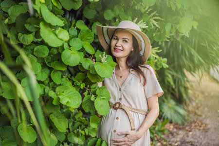 A serene and radiant pregnant woman after 40, surrounded by natures beauty in the park, cherishing the journey of motherhood with a glowing smileの写真素材