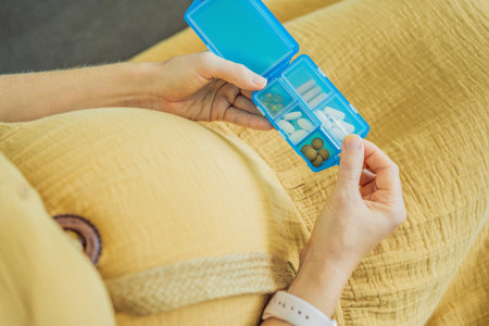 Prenatal Vitamins. Portrait Of Beautiful Smiling Pregnant Woman Holding Pill Box, Taking Supplements For Healthy Pregnancy While Sitting On Couch At Home, Free Spaceの写真素材