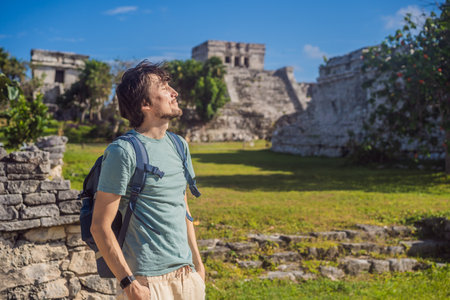 Male tourist enjoying the view Pre-Columbian Mayan walled city of Tulum, Quintana Roo, Mexico, North America, Tulum, Mexico. El Castillo - castle the Mayan city of Tulum main templeの写真素材