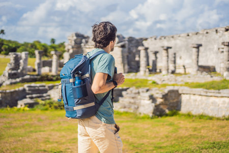 Male tourist enjoying the view Pre-Columbian Mayan walled city of Tulum, Quintana Roo, Mexico, North America, Tulum, Mexico. El Castillo - castle the Mayan city of Tulum main templeの写真素材