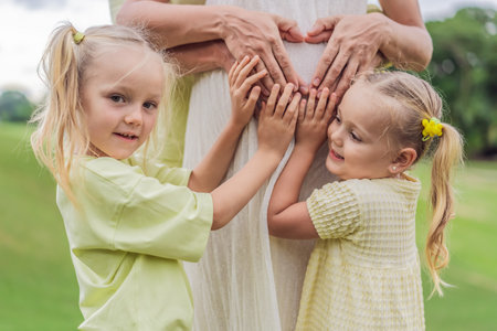 Sisters love blooms as they tenderly embrace their mothers pregnant belly, sharing anticipation and...