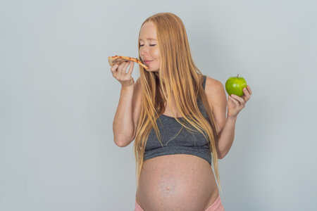 A pregnant woman faces a choice between nourishing, wholesome food and tempting fast food, highlighting the importance of healthy dietary decisions during pregnancyの写真素材