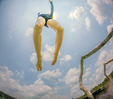 Joyful boy jumps into a turquoise lake in Mexicoの写真素材