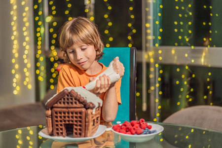 Immerse in festive delight as a boy crafts boy crafting an unconventional gingerbread house, infusing Christmas with unique creativity and festive cheer. A sweet scene of seasonal bonding and culinary funの写真素材