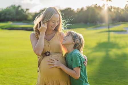 Heartwarming outdoor bonding as a pregnant mom and her son enjoy quality time together, savoring the beauty of nature and creating cherished momentsの写真素材