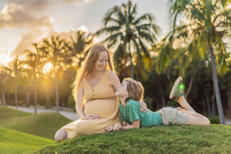Heartwarming outdoor bonding as a pregnant mom and her son enjoy quality time together, savoring the beauty of nature and creating cherished momentsの写真素材