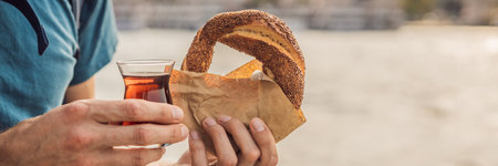 BANNER, LONG FORMAT Man in Istanbul having breakfast with Simit and a glass of Turkish tea. Glass of...