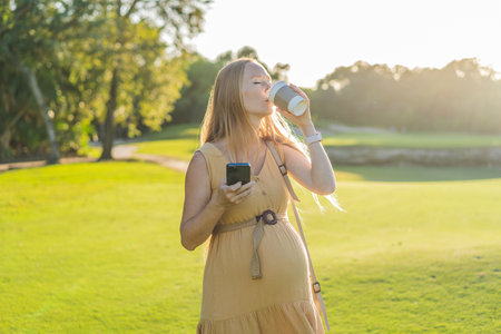 pregnant woman enjoys a cup of coffee outdoors, blending the simple pleasures of nature with the...
