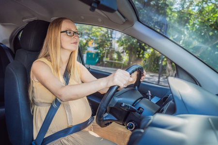 Pregnant woman driving with safety belt on in the car. Confident and capable, a pregnant woman takes...