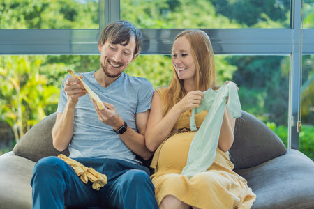 In a heartwarming scene, the future mom and dad hold their unborn babys clothes in their hands,...