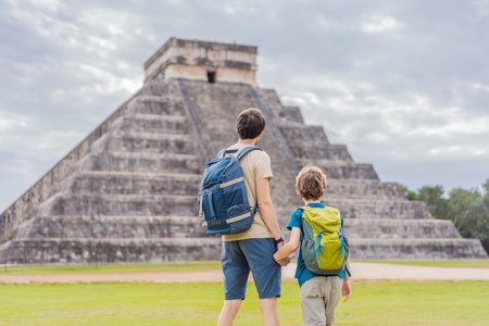 Father and son tourists observing the old pyramid and temple of the castle of the Mayan architecture...