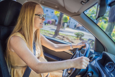 Pregnant woman driving with safety belt on in the car. Confident and capable, a pregnant woman takes...