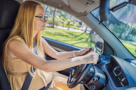 Pregnant woman driving with safety belt on in the car. Confident and capable, a pregnant woman takes...