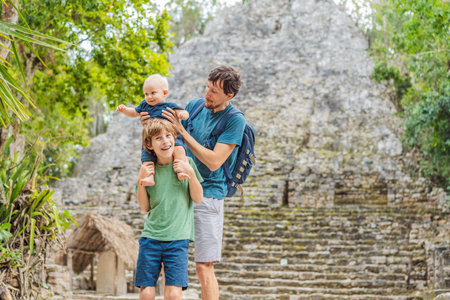 Dad with two sons tourists at Coba, Mexico. Ancient mayan city in Mexico. Coba is an archaeological area and a famous landmark of Yucatan Peninsula. Cloudy sky over a pyramid in Mexicoの写真素材