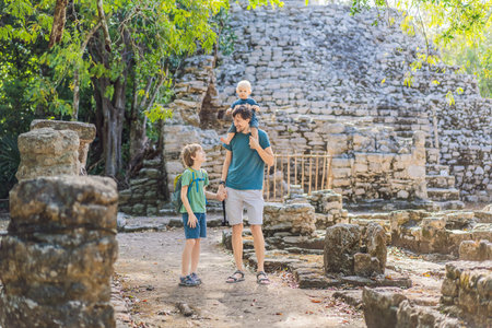 Dad with two sons tourists at Coba, Mexico. Ancient mayan city in Mexico. Coba is an archaeological area and a famous landmark of Yucatan Peninsula. Cloudy sky over a pyramid in Mexicoの写真素材