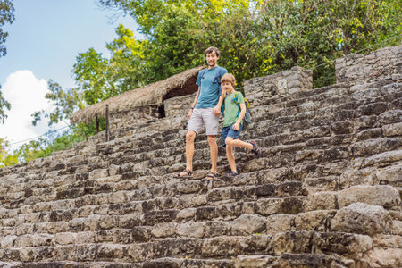 Dad and son tourists at Coba, Mexico. Ancient mayan city in Mexico. Coba is an archaeological area and a famous landmark of Yucatan Peninsula. Cloudy sky over a pyramid in Mexicoの写真素材