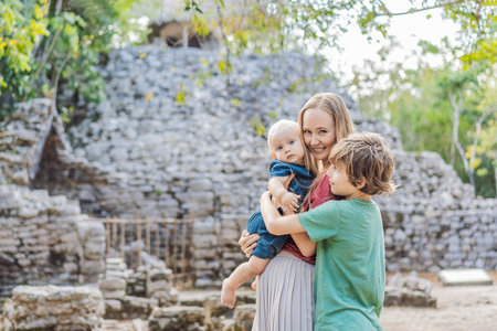 Mom and two sons tourists at Coba, Mexico. Ancient mayan city in Mexico. Coba is an archaeological area and a famous landmark of Yucatan Peninsula. Cloudy sky over a pyramid in Mexicoの写真素材