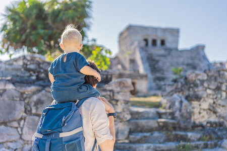 Father and son tourists enjoying the view Pre-Columbian Mayan walled city of Tulum, Quintana Roo, Mexico, North America, Tulum, Mexico. El Castillo - castle the Mayan city of Tulum main templeの写真素材