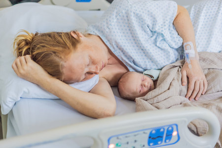 A baby lies with the mother after childbirth, resting peacefully. The serene moment captures the bond between mother and child as they begin their journey together. The hospital environment ensures a safe and comforting space for this intimate interactionの写真素材