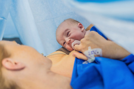 Baby on mothers chest immediately after birth in a hospital. The mother and newborn share a tender moment, emphasizing the bond and emotional connection. The medical staff ensures a safe and caring environmentの写真素材