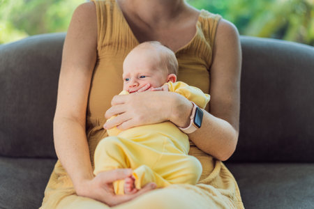 Mom with newborn baby relaxing on the sofa at home. This tender moment highlights the bond between mother and child in a comfortable and loving family environmentの写真素材