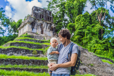 Father with his toddler son exploring the ancient pyramids of Palenque, Mexico, surrounded by dense jungle. Cultural heritage and adventure travel conceptの写真素材