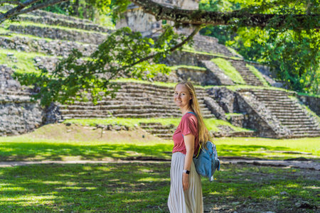 Female tourist exploring the ancient pyramids of Palenque, Mexico, surrounded by dense jungle....
